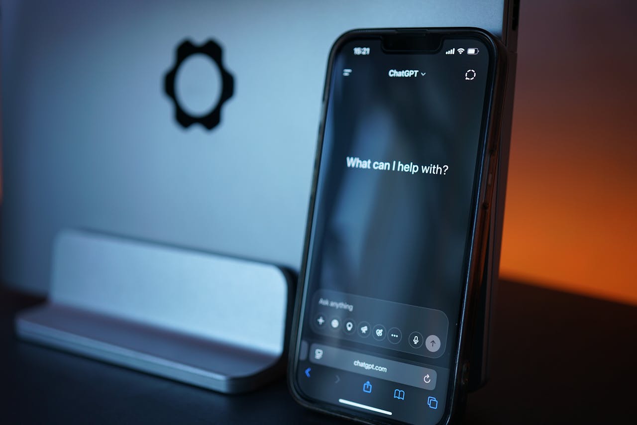 Een smartphone toont de ChatGPT-interface met de vraag "Wat kan ik voor je doen?" op een donkere achtergrond.
