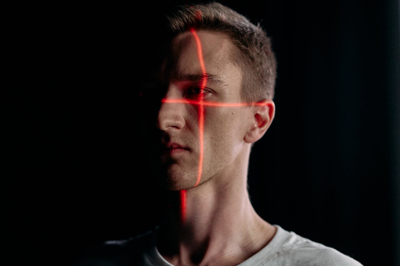 Een man met een laserschema dat zijn gezicht kruist, afgebeeld in een donker decor.