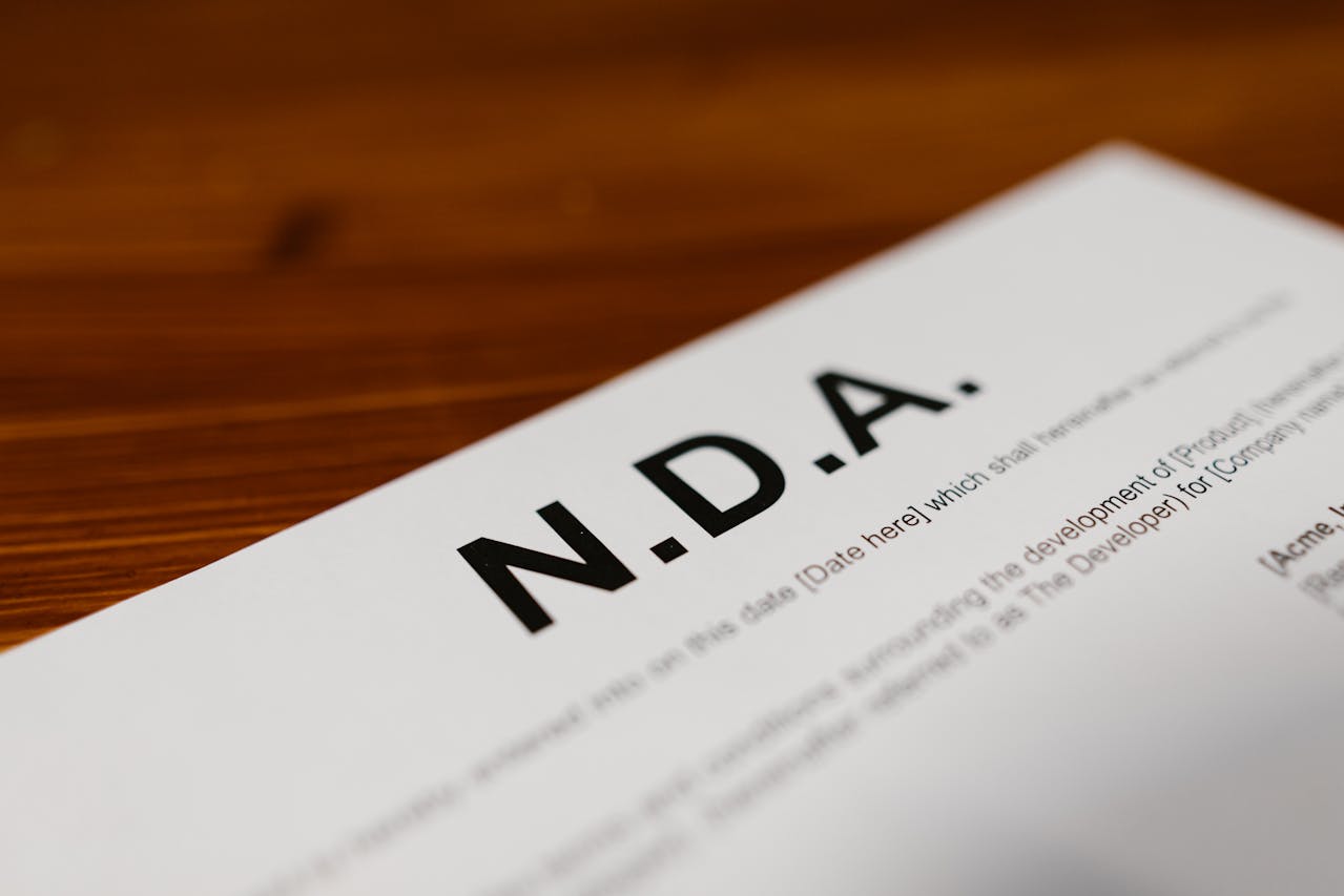 Detailopname van een niet-openbaarmakingsovereenkomst (NDA) op een houten tafel.